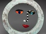sculpture of a woman ' s face in a circle with a black background