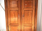 a wooden armoire in the corner of a room