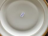 a white plate with a gold rim on a wooden table