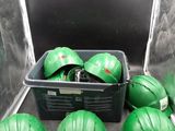 several green hard hats are sitting in a container on the floor