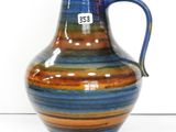 un vase rayé de bleu et d'orange posé sur une surface blanche