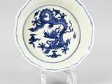 blue and white plate with a dragon on it on a stand