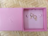 une image représentant une boîte rose contenant une paire de boucles d'oreilles