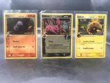 Trois cartes Pokémon sont posées sur une table.