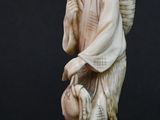 carved ivory figurine of a man with a basket on his shoulder