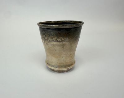 un vase noir et argent posé sur une surface blanche
