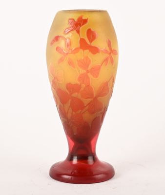 un vase rouge et jaune posé sur une surface blanche