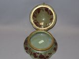 a small green and red box with a gold lid
