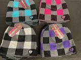 four beanies with tags on them sitting on a table