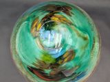 a glass bowl with a green and blue swirl inside of it