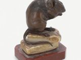 statue of a mouse sitting on a rock on a white background