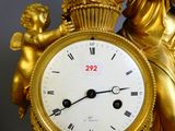 une horloge en or surmontée d'une statue représentant une femme tenant un bébé dans ses bras