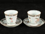 pair of porcelain cups and saucers with floral designs on them