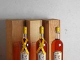 trois bouteilles d'alcool sont posées devant une caisse en bois sur une table