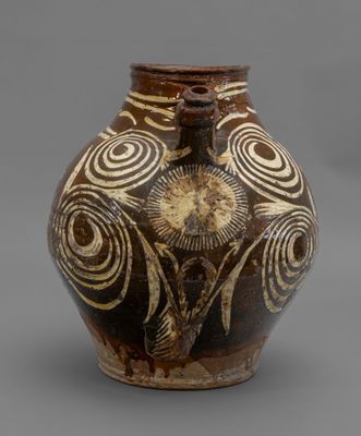brown and white vase with swirl designs on it on a gray surface