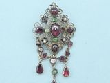 a close up of a silver broochle with red and green stones