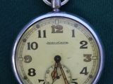 a silver pocket watch with a white face on a green cloth