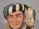 a ceramic figurine of a man with a bird on his arm