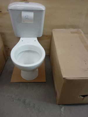 a white toilet sitting next to boxes in a room