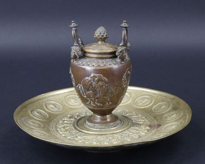 une plaque en laiton sur laquelle figure un vase, sur fond noir