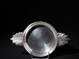 an antique silver plate with a leaf decoration on a black background