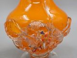 an orange glass vase with a floral design on it