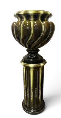 un vase posé sur un socle, sur une surface blanche