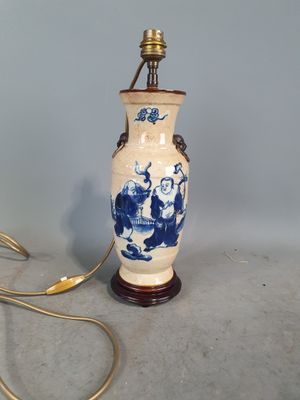 un vase bleu et blanc posé sur une table sur laquelle se trouve une lampe