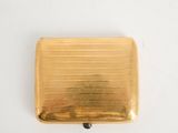 an image of a gold cigarette case sitting on top of a white table