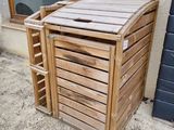 a wooden trash can sitting outside of a building