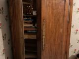 a small bed in a corner of a room next to a wooden cabinet