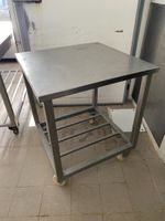 Une table carrée en inox à claies d'entrejambe, sur roulette…