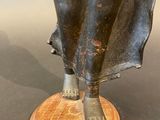 bronze statue of a woman holding a bird on a wooden base