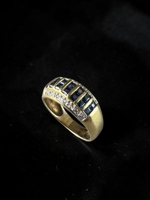 a gold ring with blue sapphires and diamonds on a black background