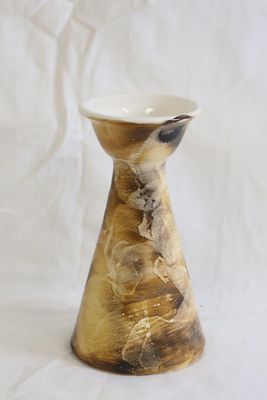 un petit vase posé sur une surface blanche