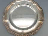 une assiette en argent posée sur un plateau blanc, bordée d'argent