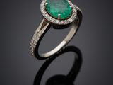 une bague en émeraude et diamant sur une surface noire