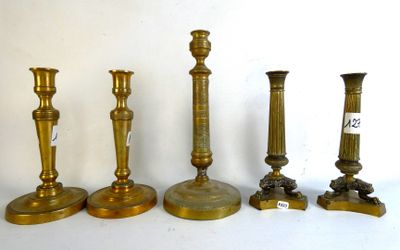 four brass candlesticks are lined up on a white surface