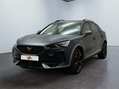Une voiture grise est garée dans une grande pièce au sol noir.