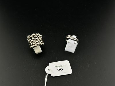 two silver rings and a tag on a black surface