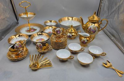 beaucoup d'assiettes et de tasses dorées et blanches sur la table
