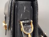 black leather handbag with gold hardware on a white surface