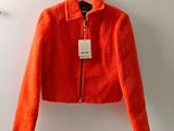 an orange jacket hanging on a hanger with a tag on it