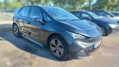 une voiture noire garée sur un parking, avec d'autres voitures en arrière-plan