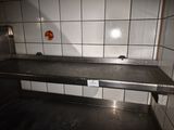 a metal counter in the middle of a tiled room