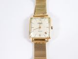 une image d'une montre-bracelet en or sur une surface blanche