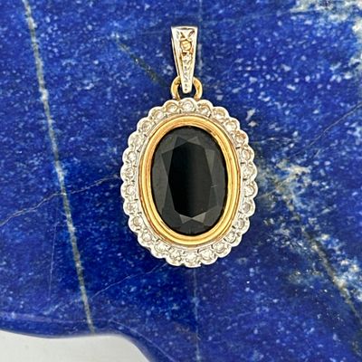 a close up of a black and gold pendant on a blue stone