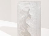 sculpture en bloc de marbre posée sur un socle blanc dans une pièce blanche