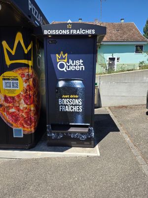 une boîte à pizza ornée d'une couronne, à côté d'une poubelle