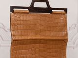 an image of a brown crocodile skin purse sitting on a table